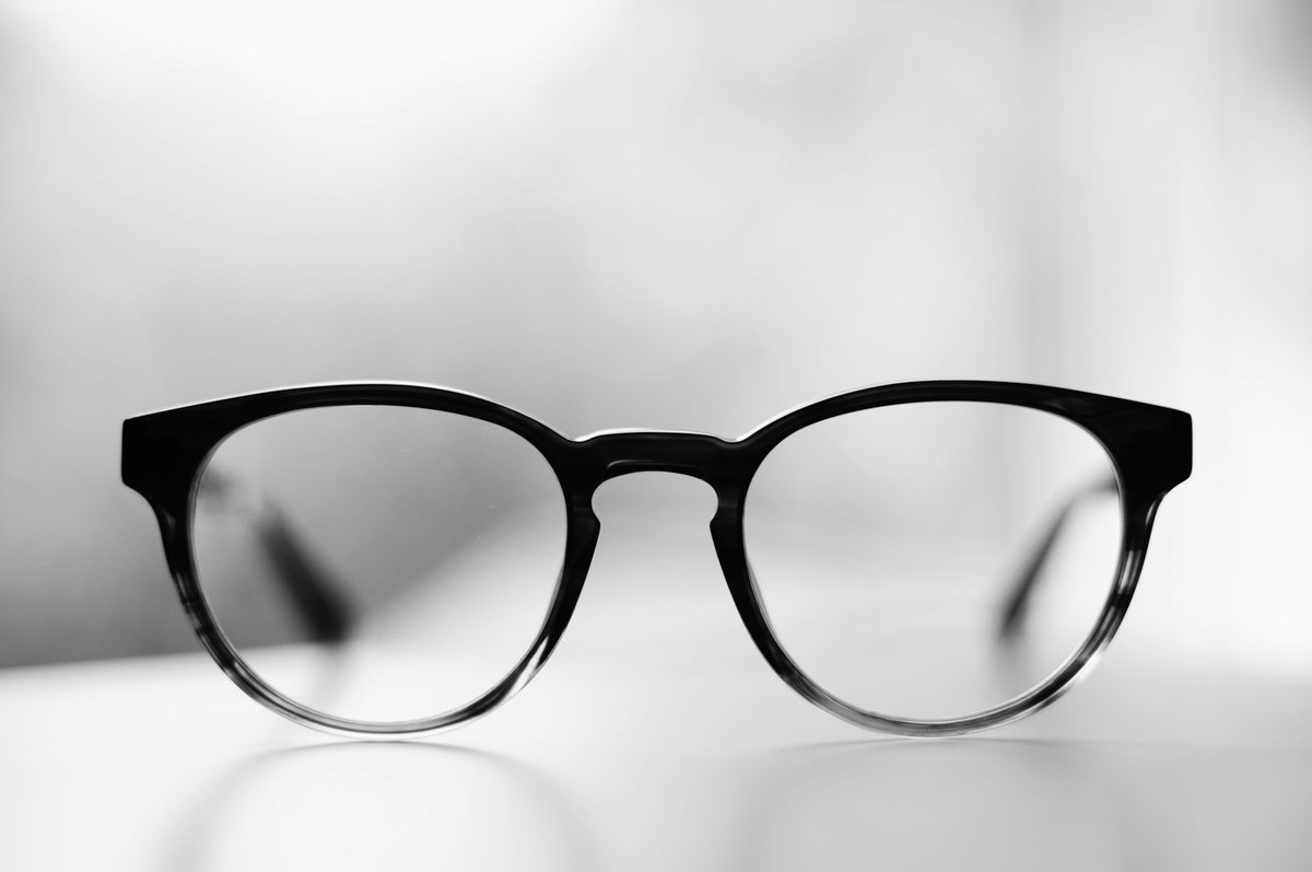 Paire de lunettes à monture noire posée sur un fond blanc, photo en noir et blanc