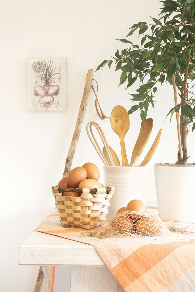 Panier d'œufs et ustensiles en bois sur le plan de travail d'une cuisine claire