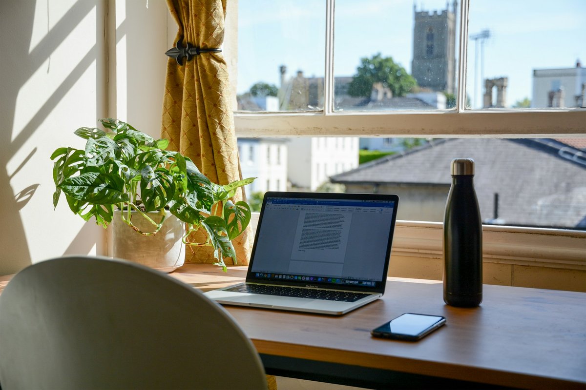 Ordinateur portable sur un bureau, devant une fenêtre ensoleillée